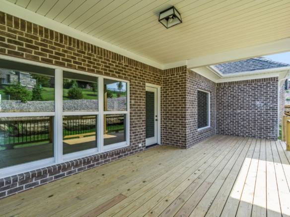Modern brick home porch with spacious wooden deck and large windows.