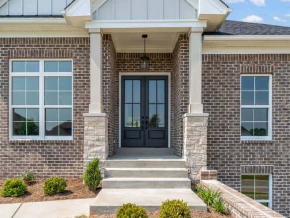 Modern brick house with a welcoming front entrance and black double doors.