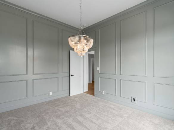 Interior wall paneling with elegant molding and a chandelier.