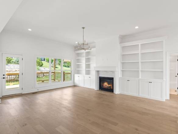 Spacious living room featuring a fireplace, built-in shelves, and large windows overlooking the back.