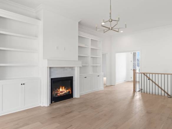 Interior of a bright, modern living room featuring a fireplace and built-in white shelves.