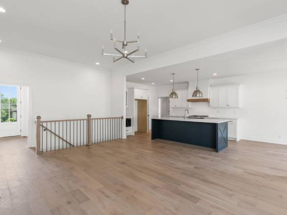 Spacious interior with white walls, hardwood floors, and contemporary lighting fixtures.
