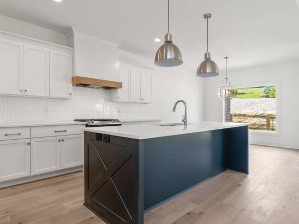 Bright, spacious kitchen featuring white cabinetry and a stylish blue island for cooking and enterta.