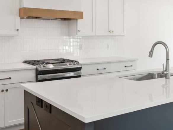 Kitchen with white cabinets, stainless steel stove, and island countertop.