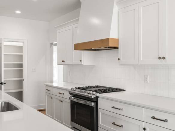 Bright white kitchen with modern cabinetry and stainless steel appliances.