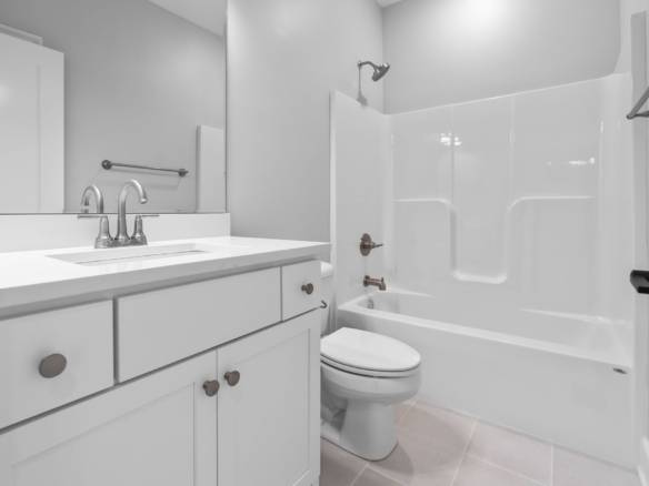 Modern bathroom with white vanity, bathtub, and neutral decor.