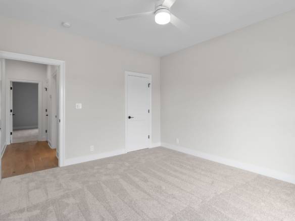 Bright, empty room with white walls and beige carpet flooring.