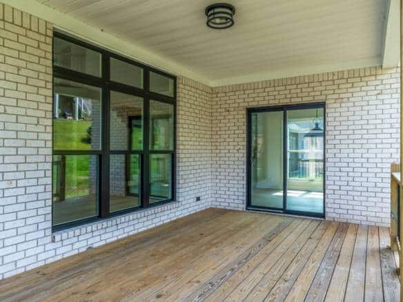 Screened porch with brick walls and large windows.