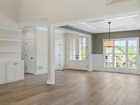 Spacious living area with big windows, light wood floors, and neutral wall colors.