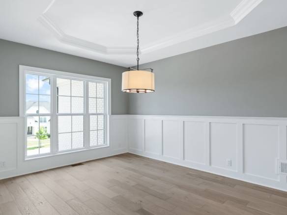 Bright, empty living room with large window and modern lighting fixture.