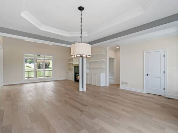 Spacious living room featuring hardwood flooring, large window, and built-in shelves, perfect for fa.