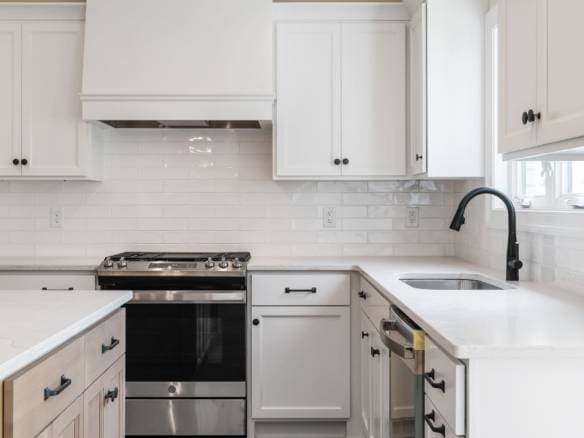 Modern white kitchen with black faucet and handles, featuring sleek cabinetry and a stainless steel.