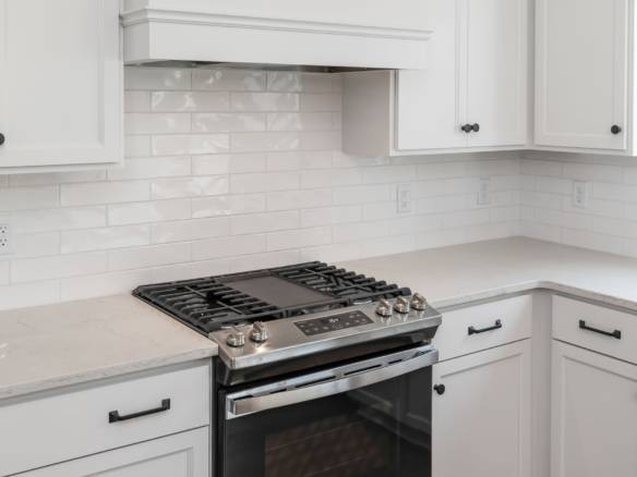 White kitchen with modern cabinetry and gas stove for cooking.