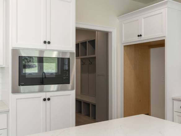 Modern white kitchen with built-in microwave and ample storage cabinets.