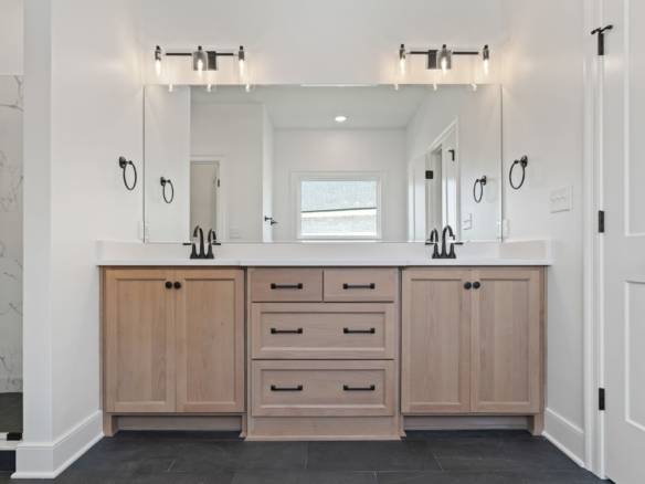 Dual-sink bathroom vanity with wooden cabinets and bright lighting.