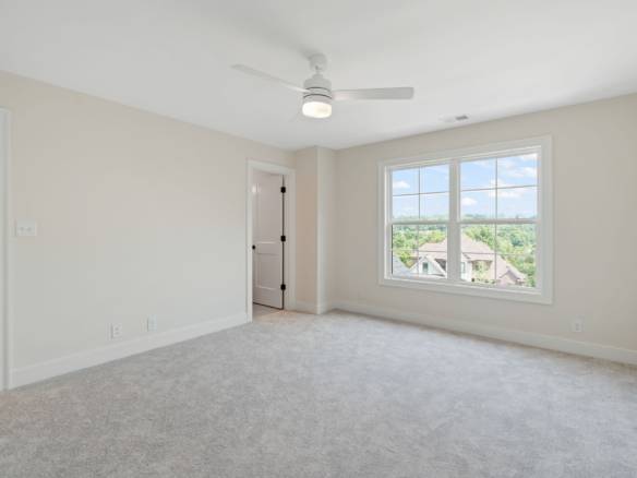 Bright, spacious bedroom with large window and neutral decor.