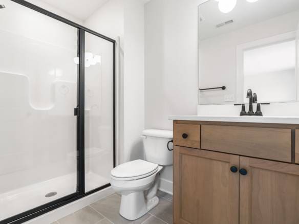 Bright modern bathroom with glass shower and wooden vanity.