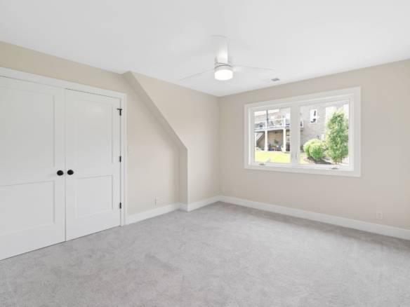 Bright, spacious bedroom featuring a large window and clean, neutral walls for versatile decorating.