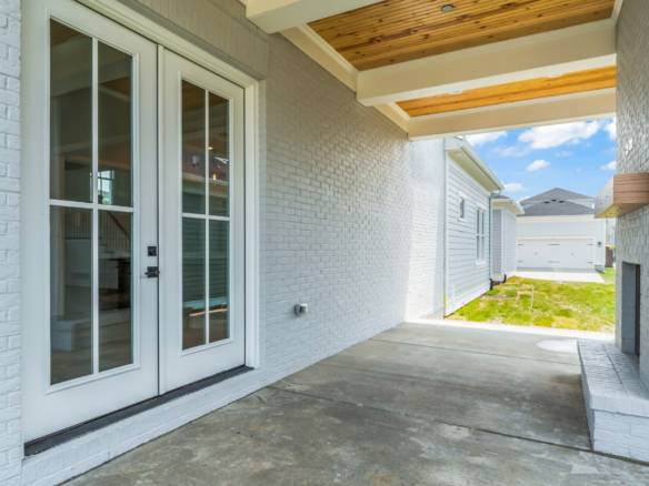 Covered patio with white brick walls, wooden ceiling, and sliding glass doors.