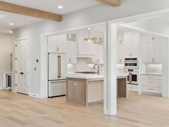 Bright, contemporary kitchen featuring white cabinetry, gold hardware, and spacious design.