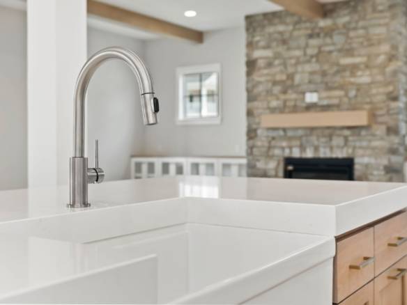 Modern kitchen with sleek white countertops and stainless steel faucet.