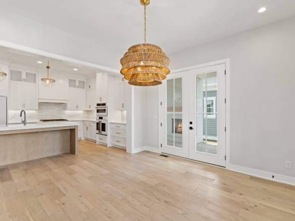 Modern kitchen with white cabinets, natural wood floors, and stylish lighting fixtures.
