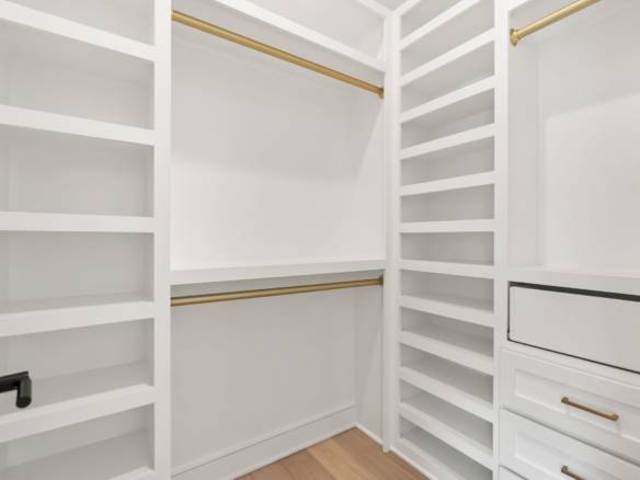 Custom walk-in closet with white shelving and drawers.