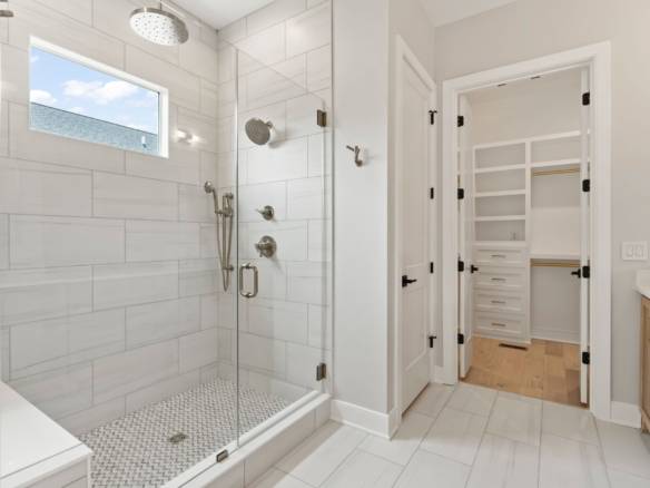 Bright, spacious walk-in shower with glass enclosure and rainfall showerhead.