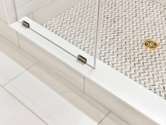 Glass shower door with metal hinges and textured shower floor.