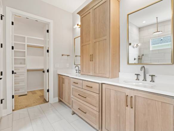 Bright bathroom featuring dual vanities, large mirror, and ample storage space.