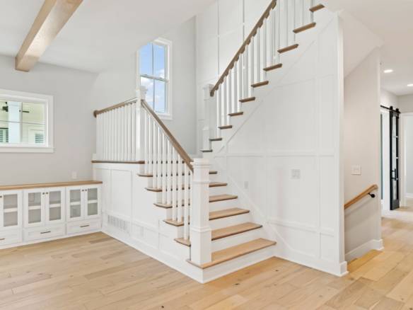 Elegant interior staircase with white paneling and wooden steps at 6331 Pond Lily Street.