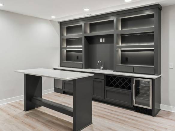 Custom basement bar with dark cabinetry and wine rack for entertainment spaces.