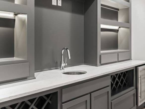 Elegant gray kitchen cabinets with wine storage and mini fridge.