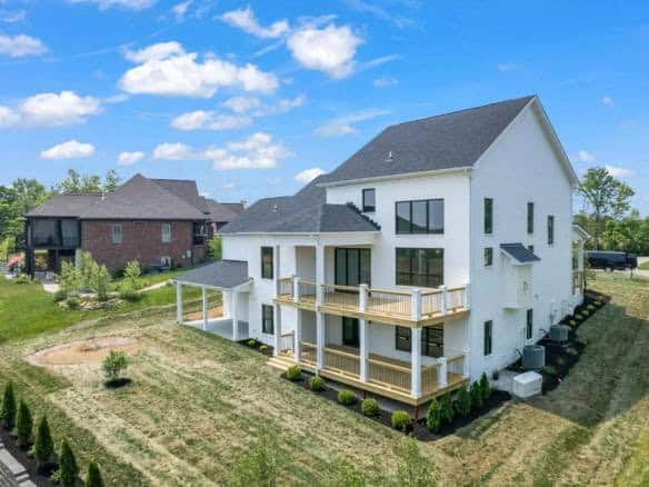 Modern white house with multiple decks and large windows.