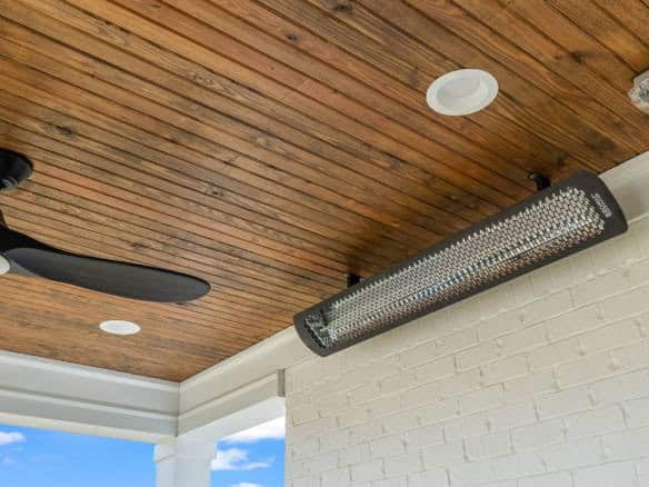 Porch ceiling with wood panels, ceiling fan, and stylish light fixture.
