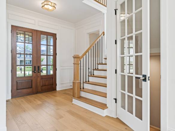 Entryway featuring a wooden front door and staircase with wooden steps and black railing.