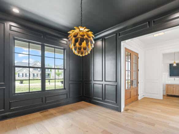Interior view of a room with dark gray paneled walls, a large window, and a stylish pendant light.
