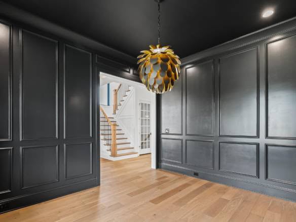 Interior design featuring dark gray wall panels and a stylish gold pendant light fixture.