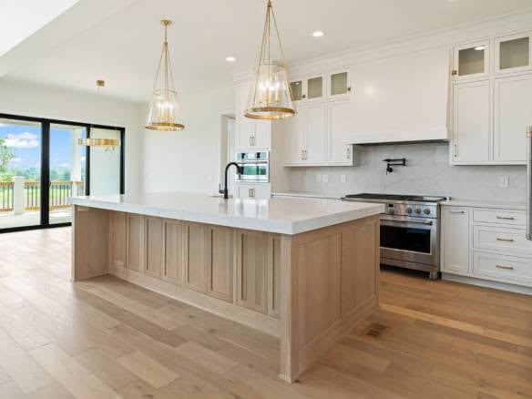 Modern white kitchen featuring a large island, pendant lights, and sleek cabinetry at 17423 Shakes C.
