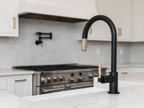 Modern kitchen sink with black faucet and marble countertop.