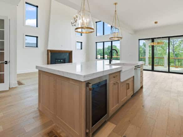 Bright, spacious kitchen featuring large windows, high ceilings, and a central island with pendant l.