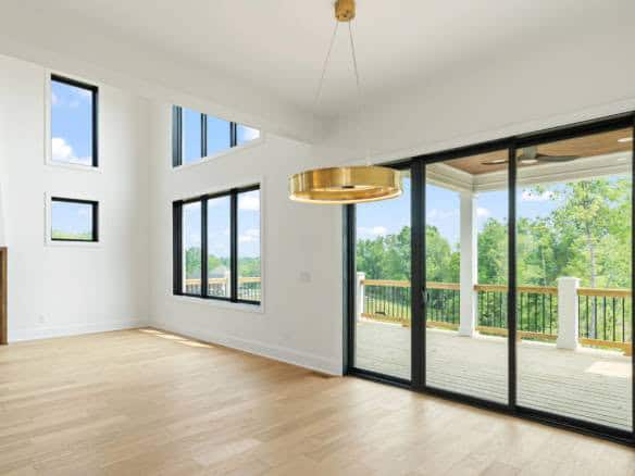 Bright living room with expansive windows and sliding glass doors leading to a balcony. Features hig.