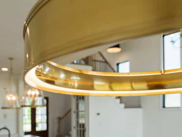 Gold chandelier hangs from ceiling in a bright, open-concept home interior.