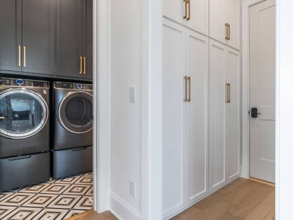 Laundry room with white cabinetry and black appliances for efficient household chores.