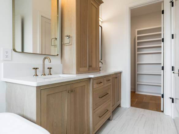 Bathroom vanity with wooden cabinets, mirror, and open closet at 17423 Shakes Creek Drive.