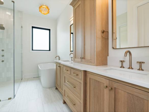 Bathroom with wooden cabinets, double sinks, and a walk-in shower.