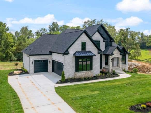 New construction home with black roof and white exterior, landscaped yard.