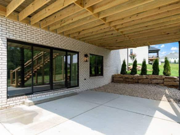 Covered patio with brick exterior, concrete floor, and landscaped garden.