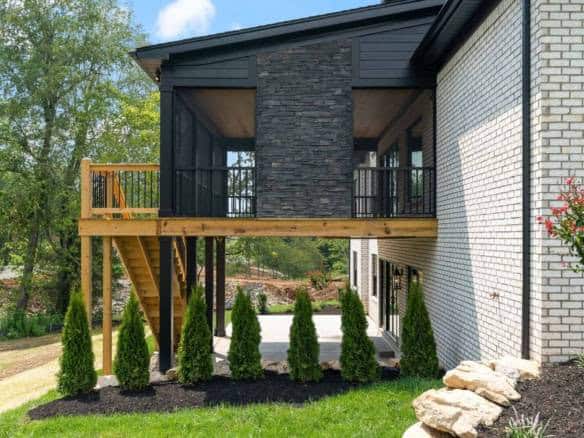 Elevated wooden deck attached to a modern house with black and white exterior.