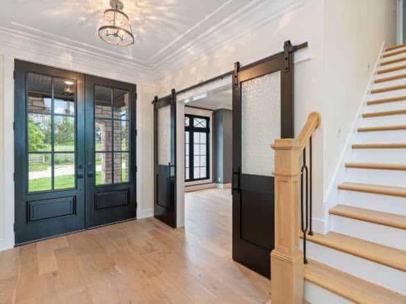 Modern entryway featuring black sliding barn doors and a staircase with wooden steps.